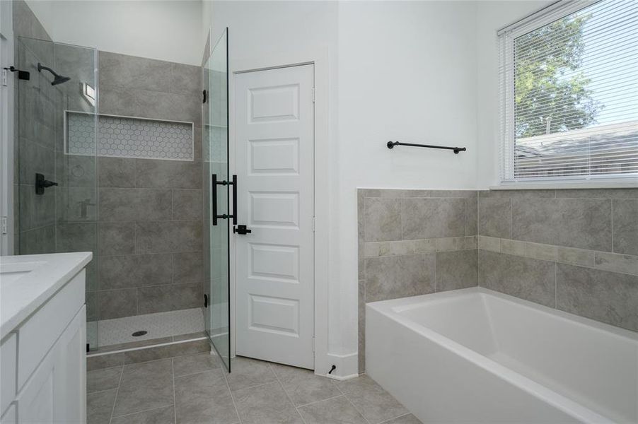 Bathroom featuring independent shower and bath, vanity, and tile patterned flooring