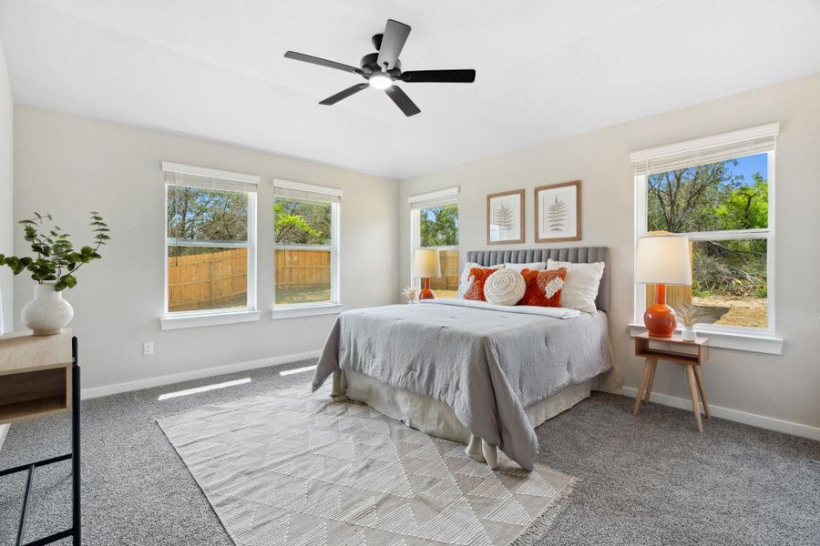 Carpeted primary bedroom featuring a ceiling fan lots of natural light Carpeted primary bedroom featuring a ceiling fan lots of natural light