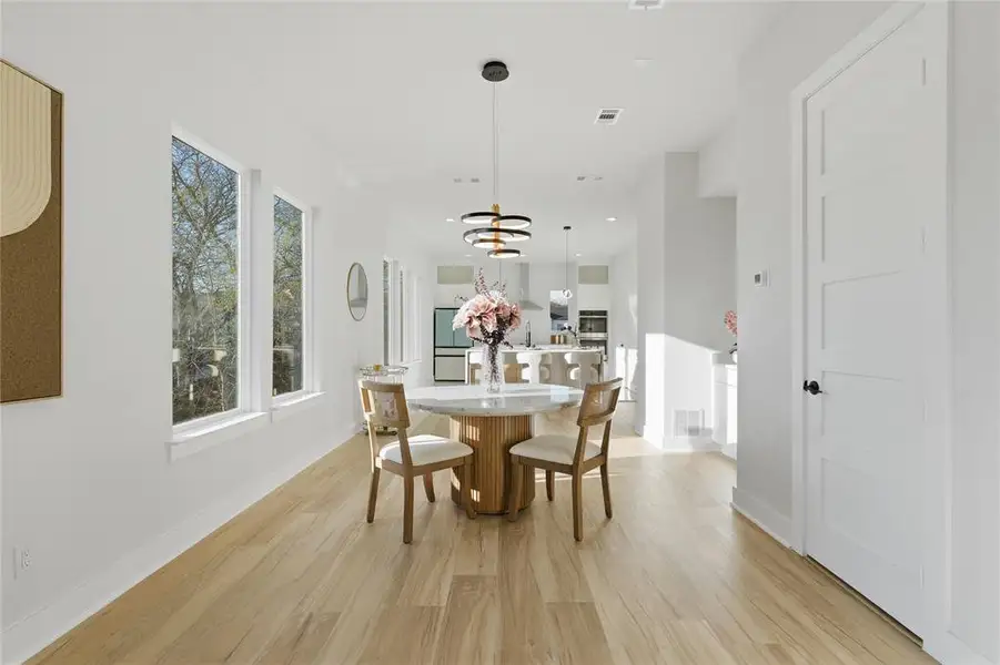 Dining space with light wood-style flooring and suspended lighting Dining space with light wood-style flooring and suspended lighting