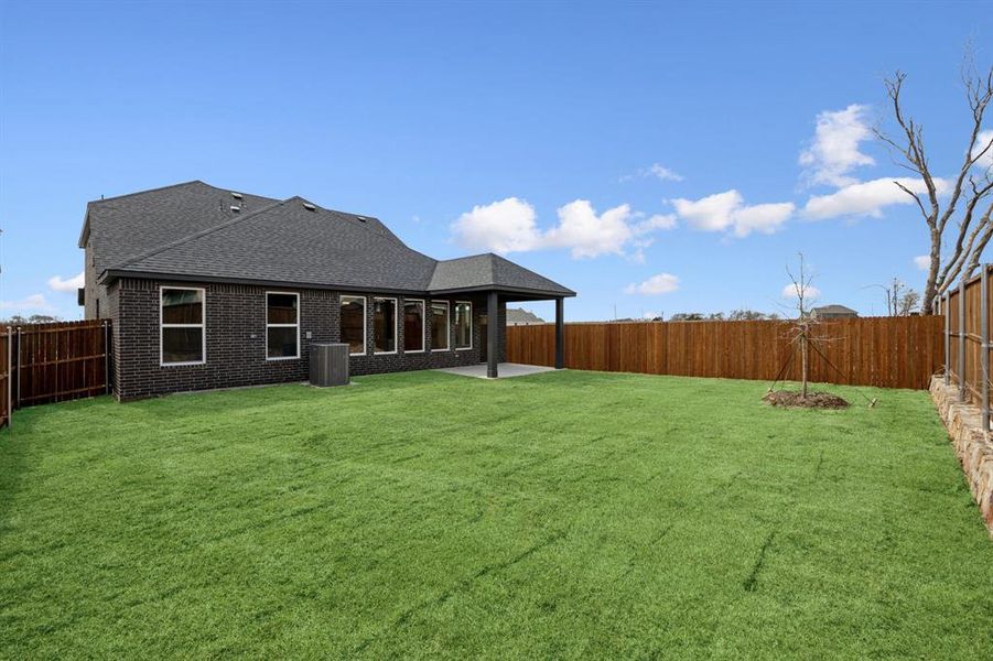 Rear view of house with a lawn and a fenced backyard