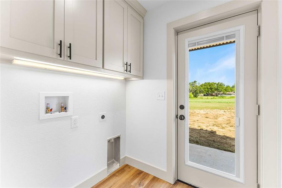 Laundry room with light wood finished floors, hookup for a washing machine, electric dryer hookup, and cabinet space Laundry room with light wood finished floors, hookup for a washing machine, electric dryer hookup, and cabinet space