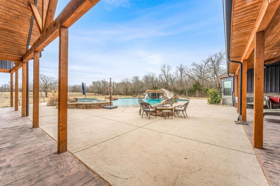 View of patio / terrace with an outdoor fire pit and a pool with connected hot tub