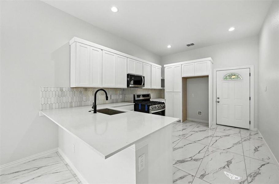 Kitchen with white cabinets, a peninsula, light marble finish flooring, tasteful backsplash, and recessed lighting