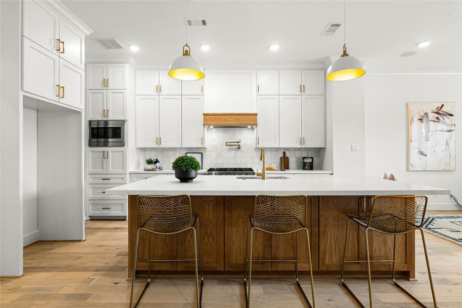 This stunning kitchen showcases elegant gold hardware, a spacious island with built-in storage perfect for utensils, cups, and serving ware, and sleek built-in appliances that combine function with modern style.