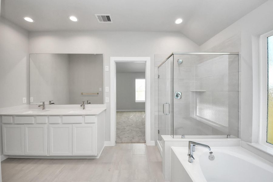 Escape to a spa-like oasis in this primary bathroom. Enjoy a walk-in shower with tile surround, a separate garden tub with custom detailing, and an elegant vanity featuring light countertops, modern hardware, and beautiful recessed lights. Experience luxury and relaxation in every detail. Sample photo of completed home with similar floor plan. Actual colors and selections may vary. Escape to a spa-like oasis in this primary bathroom. Enjoy a walk-in shower with tile surround, a separate garden tub with custom detailing, and an elegant vanity featuring light countertops, modern hardware, and beautiful recessed lights. Experience luxury and relaxation in every detail. Sample photo of completed home with similar floor plan. Actual colors and selections may vary.