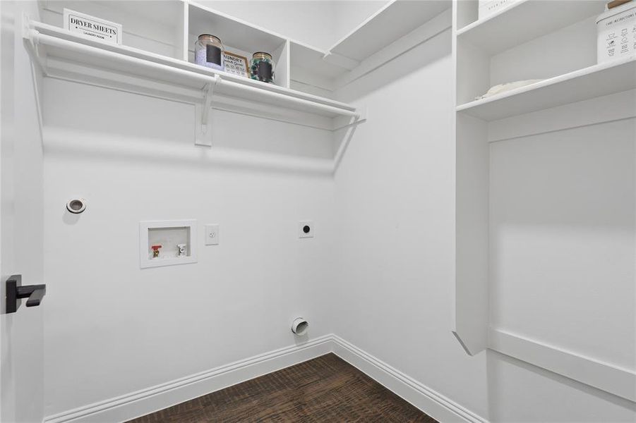 Laundry area featuring wood-finish flooring, white walls, and built-in shelving Laundry area featuring wood-finish flooring, white walls, and built-in shelving