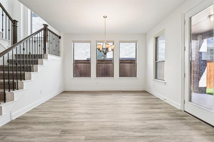 Unfurnished dining area with light wood-style floors, a chandelier, and stairs Unfurnished dining area with light wood-style floors, a chandelier, and stairs