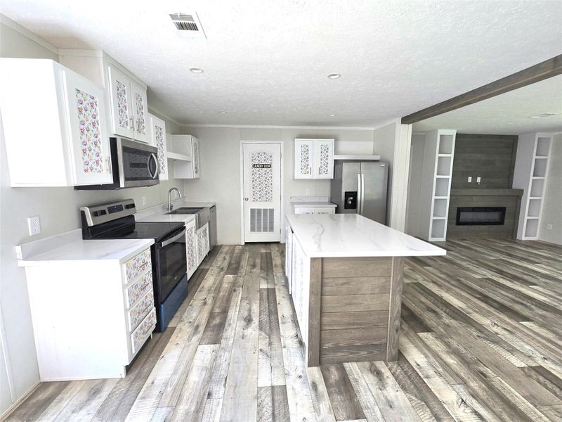 This inviting kitchen, viewed from the dining room, features modern appliances, elegant cabinetry with floral accents, and a spacious island perfect for culinary creations and family gatherings. This inviting kitchen, viewed from the dining room, features modern appliances, elegant cabinetry with floral accents, and a spacious island perfect for culinary creations and family gatherings.