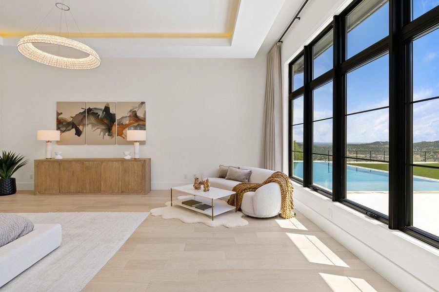 Floor-to-ceiling windows frame sweeping outdoor views and a pool, illuminating the expansive living area with natural light.