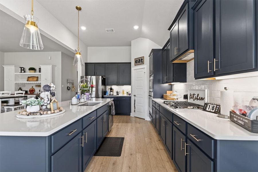 This kitchen features modern navy blue cabinets, sleek white countertops, and stainless steel appliances, offering a stylish and functional cooking space.
