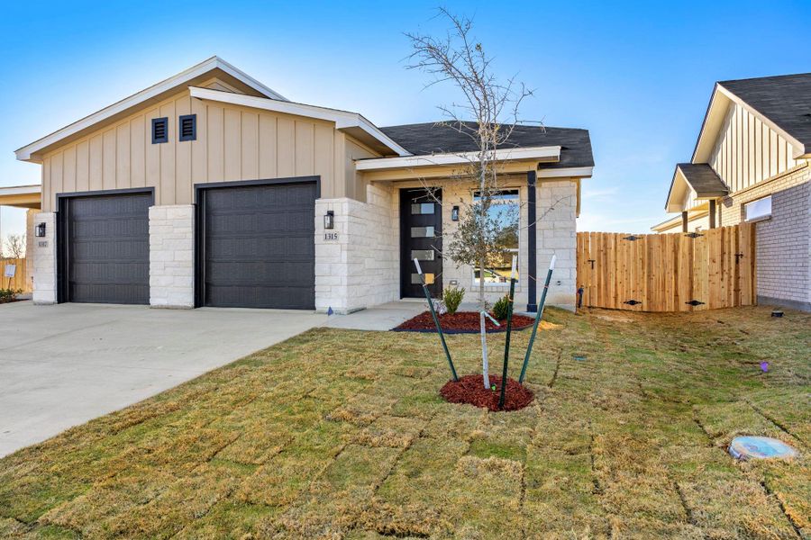 View of front facade featuring board and batten siding, driveway, and a garage