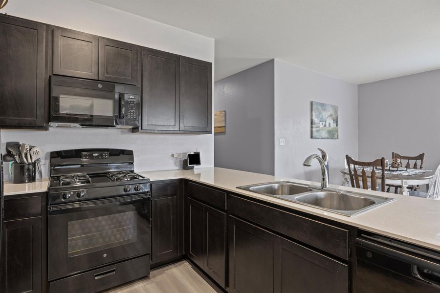 Kitchen with black appliances, light quartz countertops, and LVP floors Kitchen with black appliances, light quartz countertops, and LVP floors