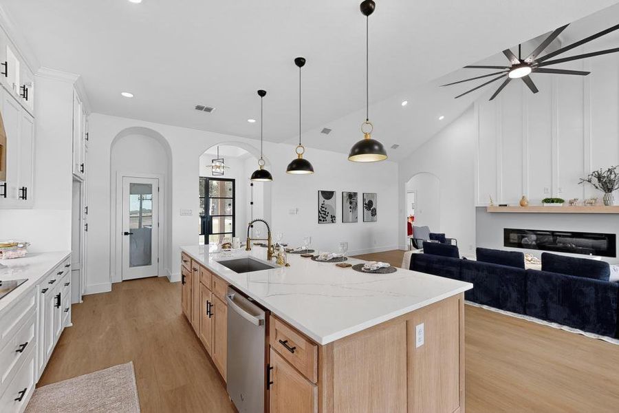 Kitchen featuring arched walkways, open floor plan, light wood-type flooring, ceiling fan, and stainless steel dishwasher