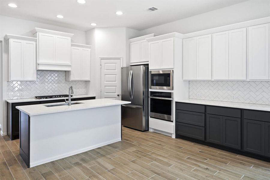 A modern kitchen complemented by warm wood look flooring.