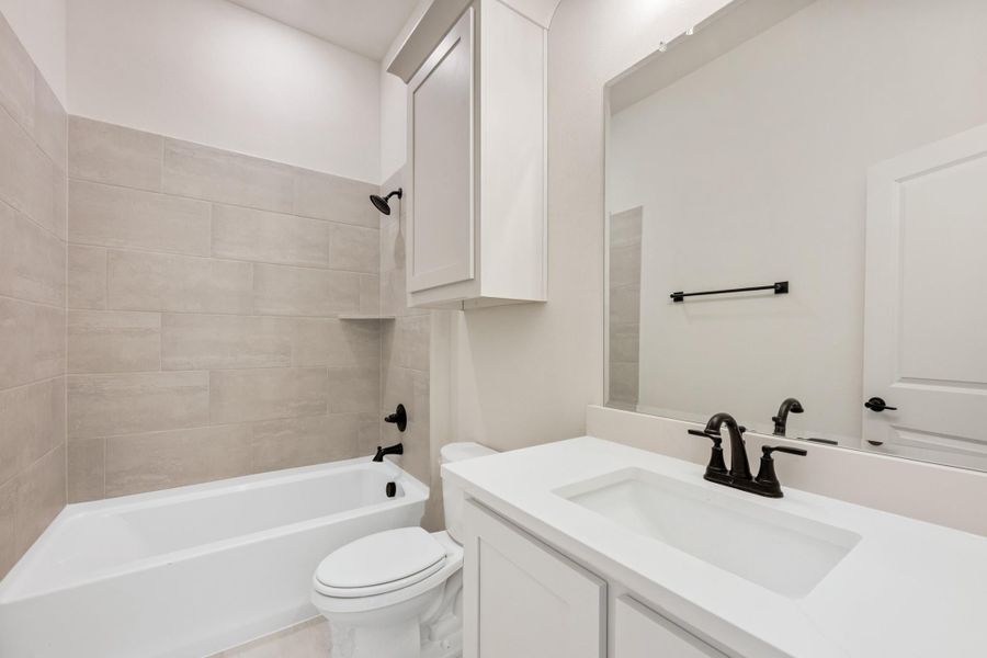 Bathroom with white vanity, tub-shower combo with beige tile surround, and black fixtures Bathroom with white vanity, tub-shower combo with beige tile surround, and black fixtures