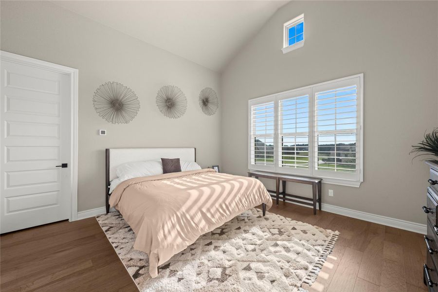 Slanted high ceilings elevate this inviting bedroom, offering warm hardwood flooring and natural light through large windows. Slanted high ceilings elevate this inviting bedroom, offering warm hardwood flooring and natural light through large windows.