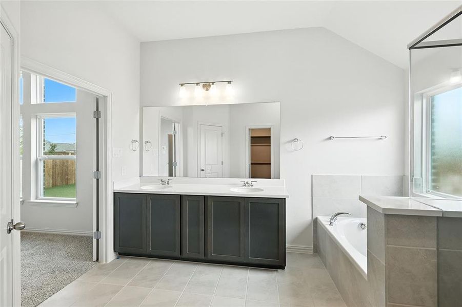 Bathroom featuring plenty of natural light, double vanity, a bath, and light tile patterned flooring Bathroom featuring plenty of natural light, double vanity, a bath, and light tile patterned flooring