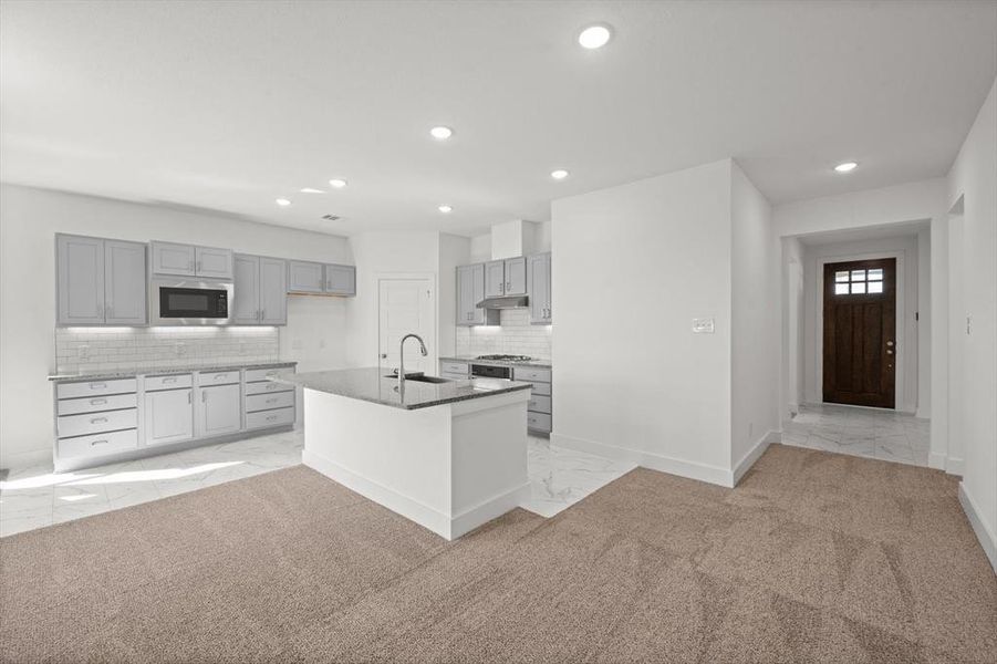 Kitchen with island breakfast bar, granite countertops, tile backsplash and gray cabinetry