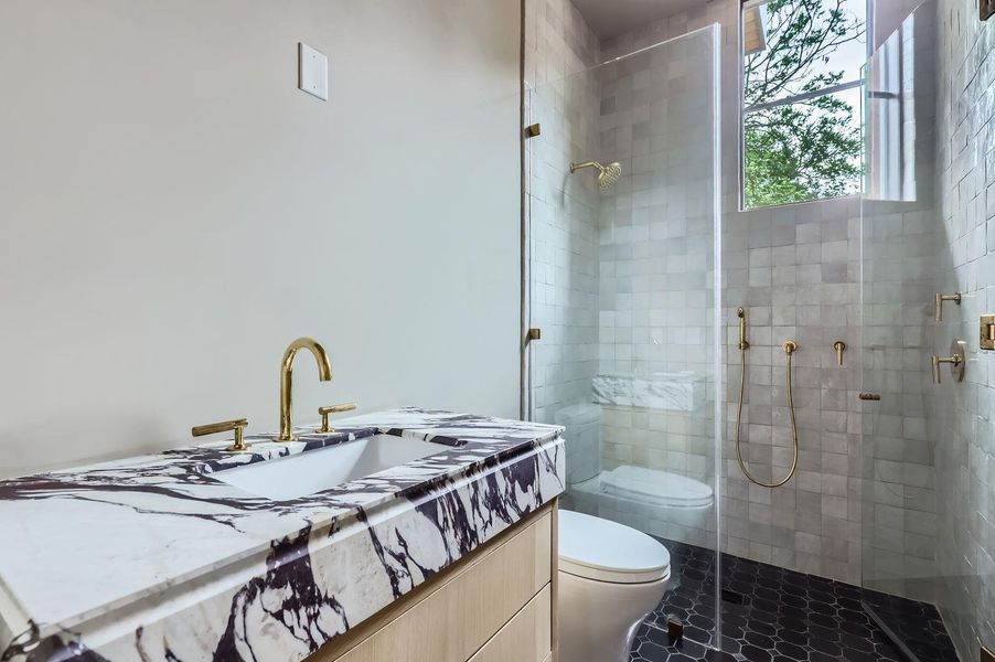 A well-appointed bathroom features a striking marble vanity and a spacious, glass-enclosed shower.