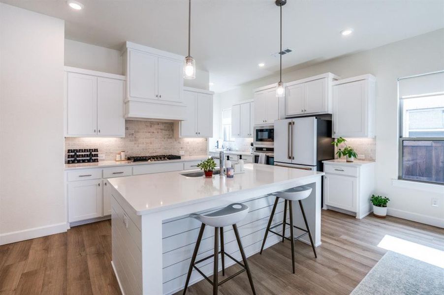 Kitchen with a kitchen breakfast bar, white cabinets, hanging light fixtures, decorative backsplash, and recessed lighting Kitchen with a kitchen breakfast bar, white cabinets, hanging light fixtures, decorative backsplash, and recessed lighting