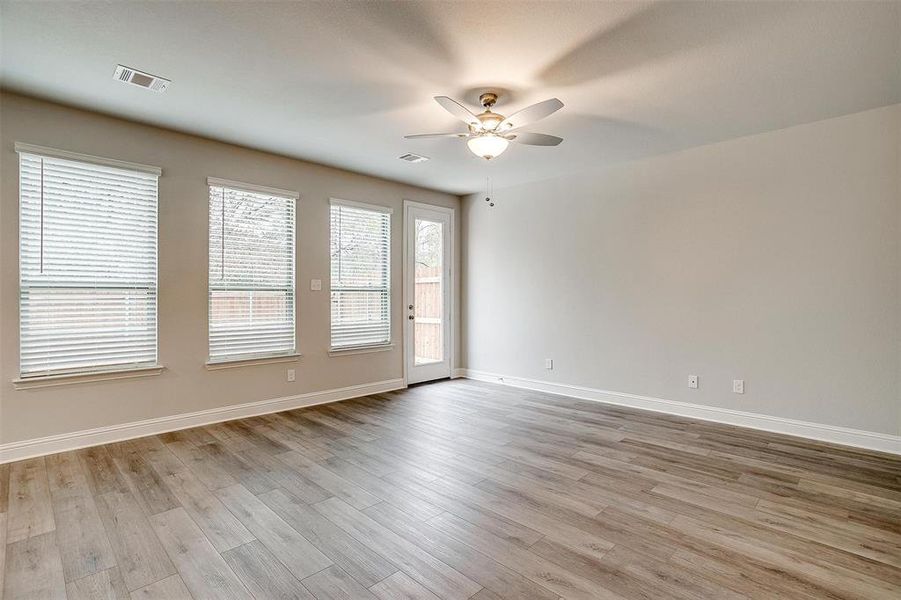 Spare room with a ceiling fan, visible vents, baseboards, and wood finished floors