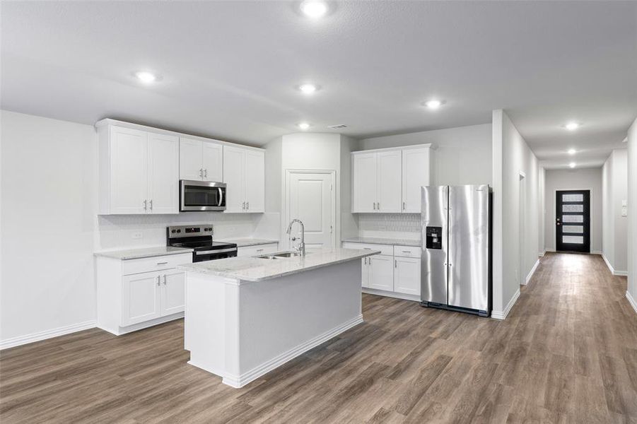 Kitchen with stainless steel appliances, decorative backsplash, dark wood-style floors, a kitchen island with sink, and recessed lighting Kitchen with stainless steel appliances, decorative backsplash, dark wood-style floors, a kitchen island with sink, and recessed lighting