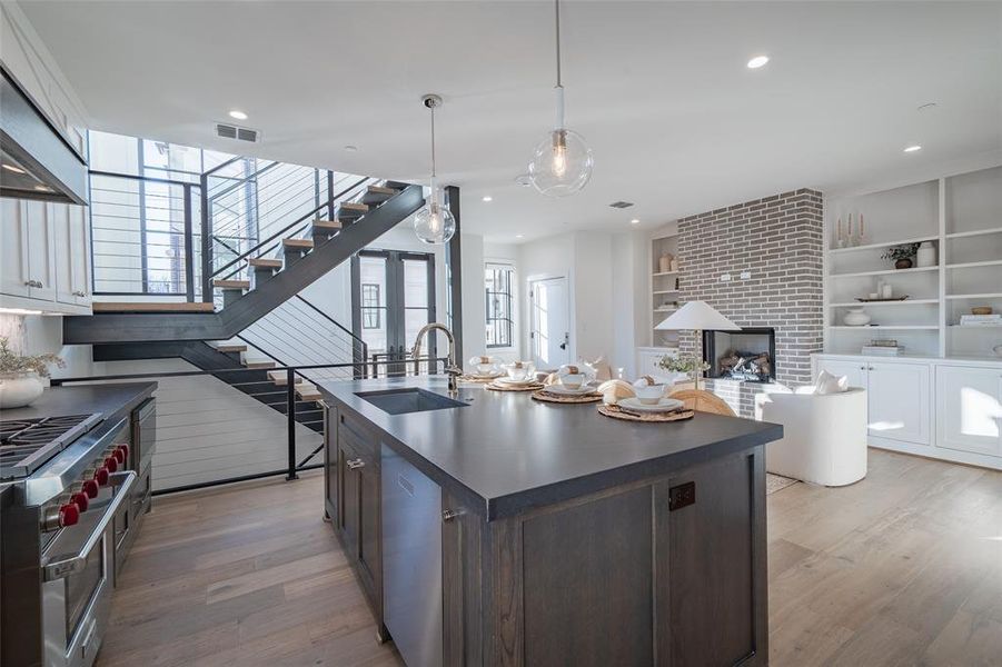 Kitchen featuring dark brown cabinetry, sink, an island with sink, white cabinets, and appliances with stainless steel finishes