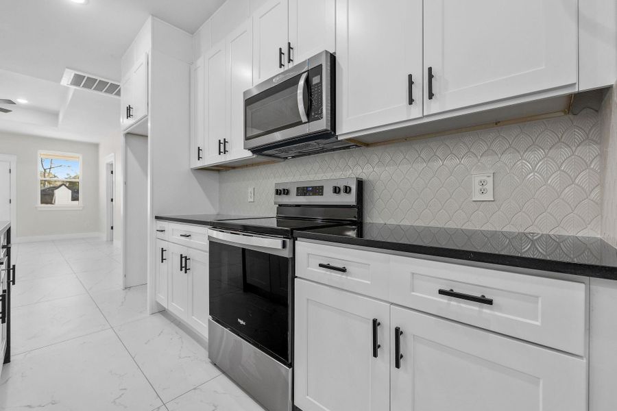 Kitchen with white cabinets and stainless-steel appliances microwave, stove, dishwasher