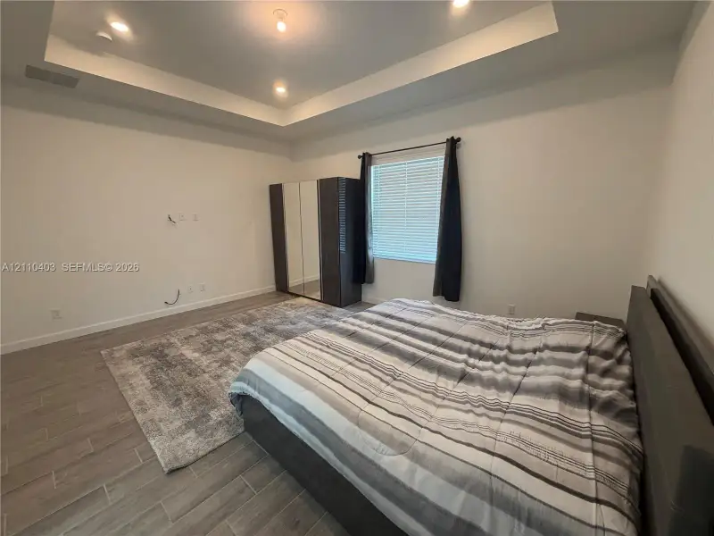 Tray ceiling with recessed lighting and wood-finish tile flooring