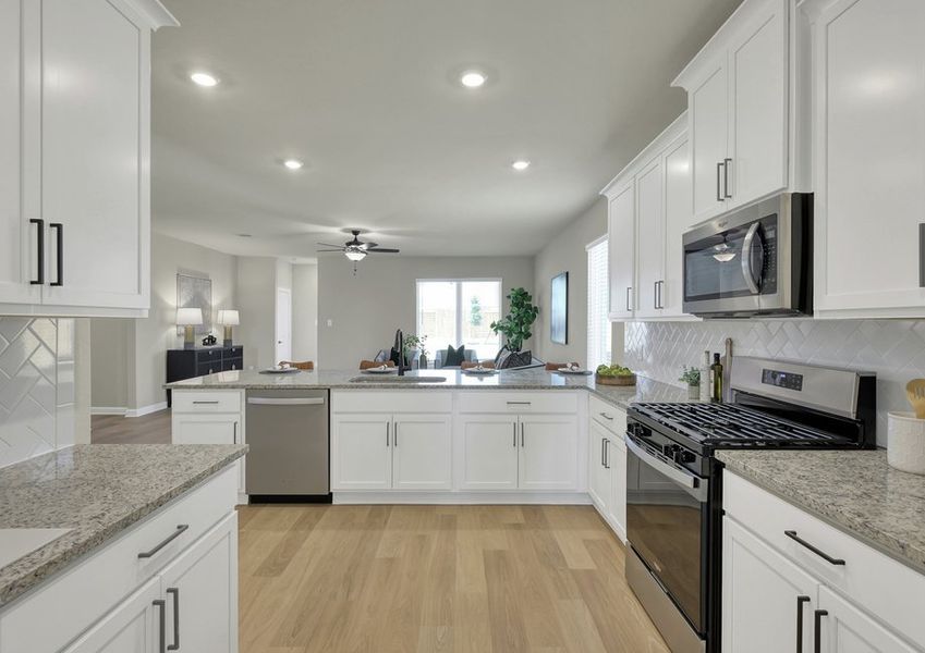 Kitchen detail featuring a stainless gas range and microwave, granite countertops, and white cabinetry.