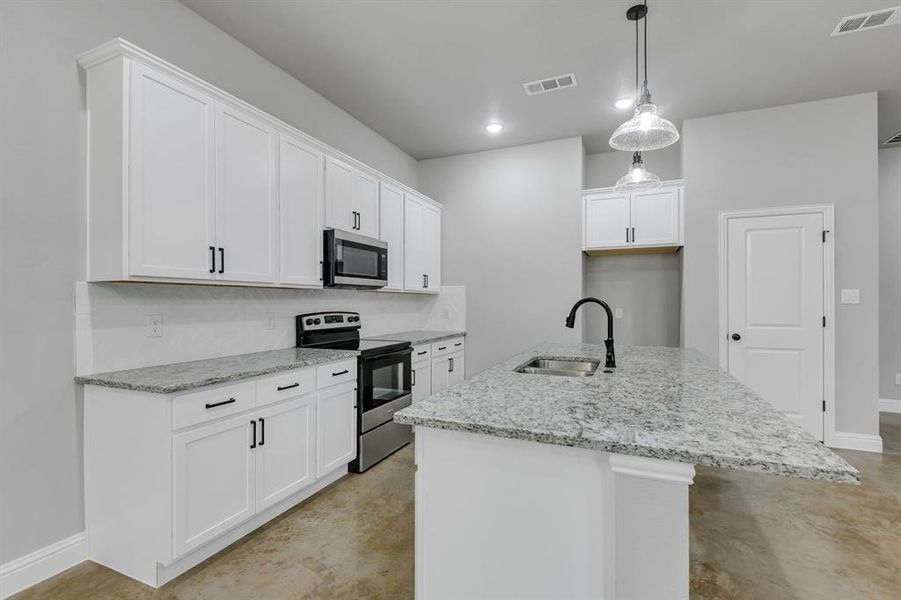 Kitchen featuring finished concrete flooring, appliances with stainless steel finishes, light stone countertops, a kitchen island with sink, and recessed lighting