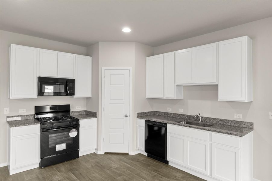 Kitchen featuring black appliances, dark wood-style floors, white cabinetry, dark stone countertops, and recessed lighting