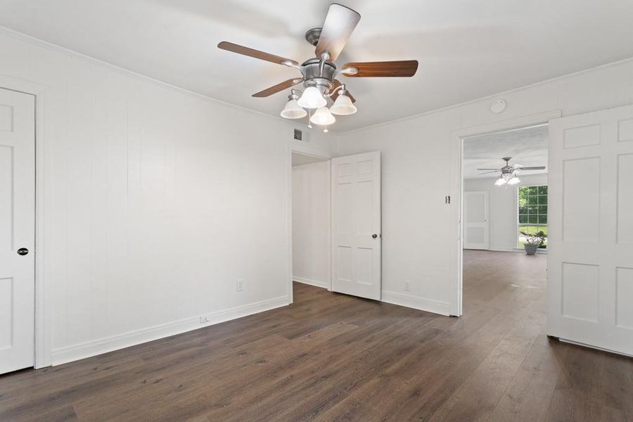 Spare room with dark wood-style floors, a ceiling fan, ornamental molding, and baseboards