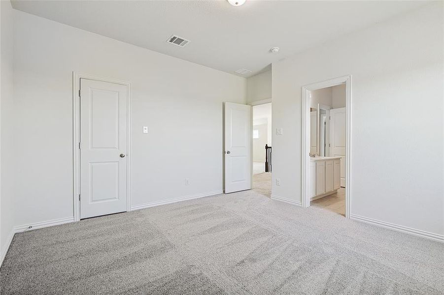 Unfurnished bedroom featuring connected bathroom and light colored carpet