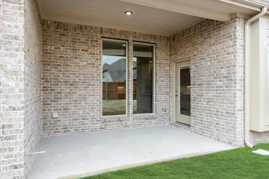 Covered back patio with concrete floor, brick exterior wall, large window, and back door entry Covered back patio with concrete floor, brick exterior wall, large window, and back door entry