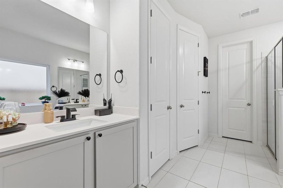 Full bath featuring vanity, light tile patterned floors, a closet, and a stall shower
