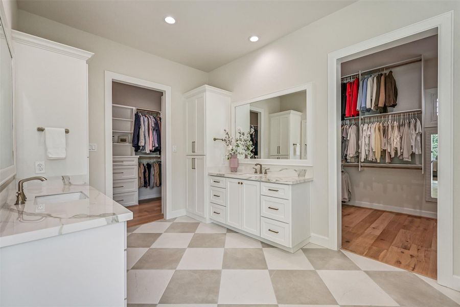 Designed with exceptional function, the primary bath offers separate vanities positioned between two generously sized custom closets, providing each side with dedicated storage while maintaining a bright, open feel.