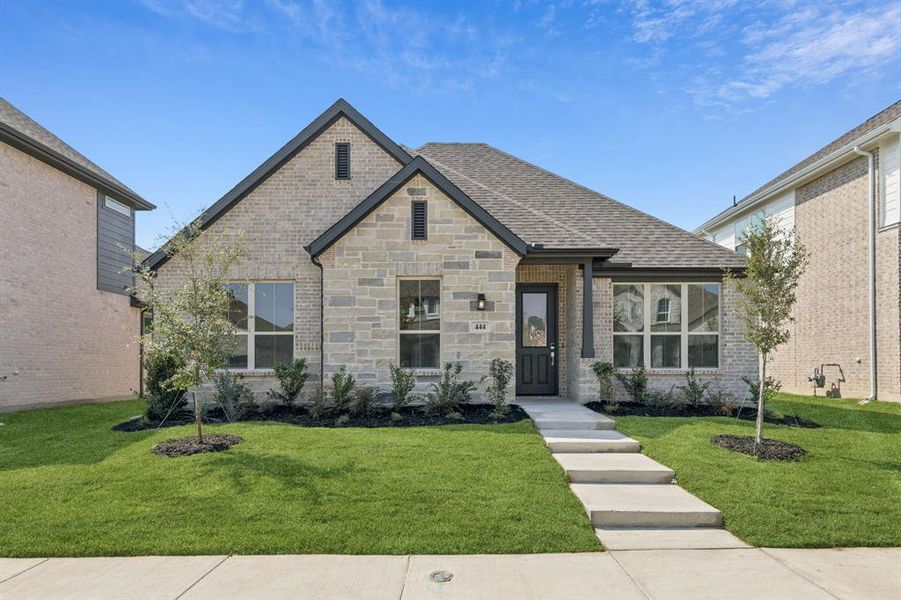 French country home featuring a front lawn, a shingled roof, and brick siding