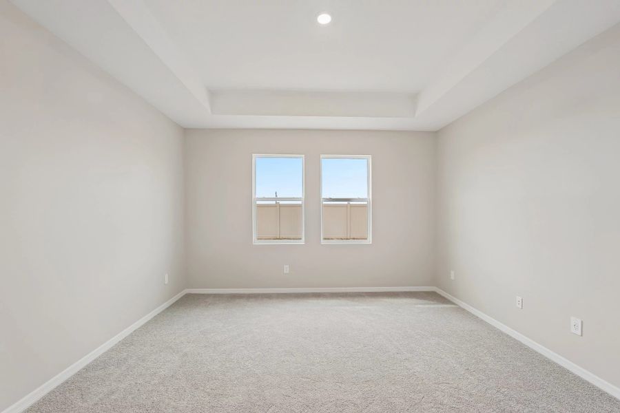 Primary bedroom features a tray ceiling and two large windows