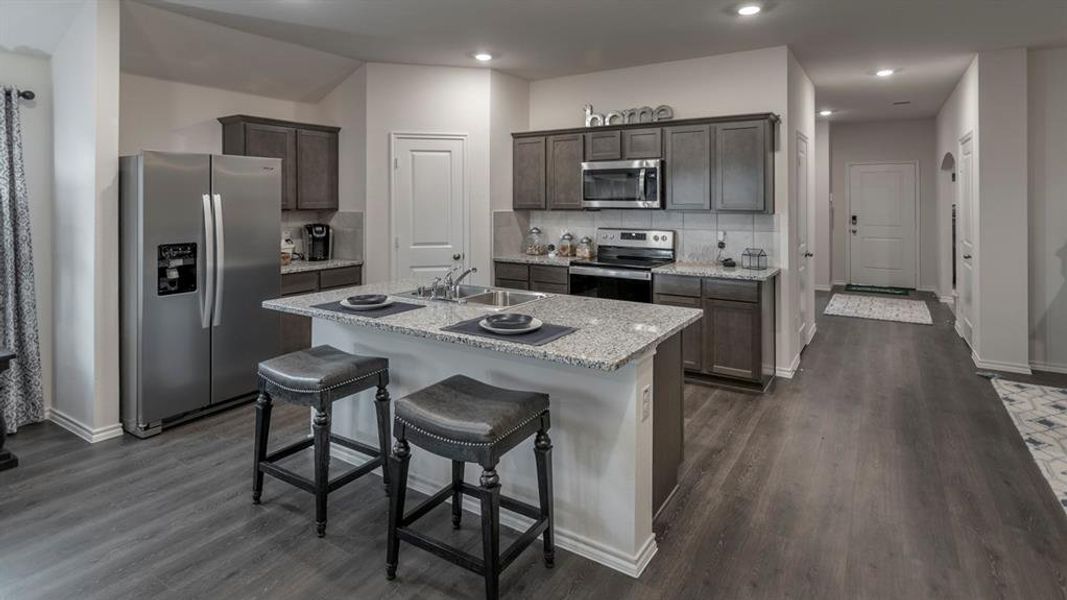 Kitchen featuring stainless steel appliances, a breakfast bar area, a center island with sink, backsplash, and recessed lighting