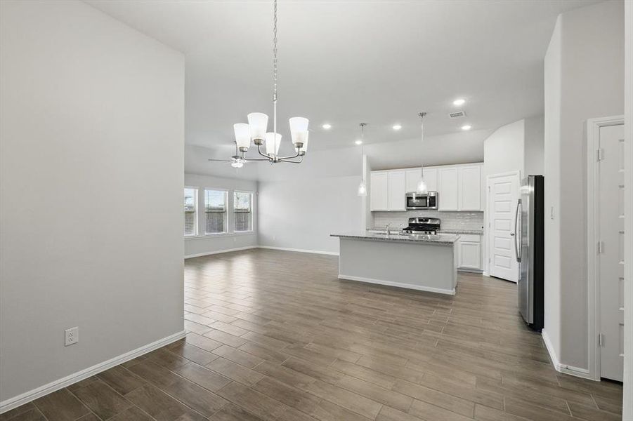 Kitchen with open floor plan, a chandelier, a center island with sink, hanging light fixtures, and dark wood-style floors Kitchen with open floor plan, a chandelier, a center island with sink, hanging light fixtures, and dark wood-style floors