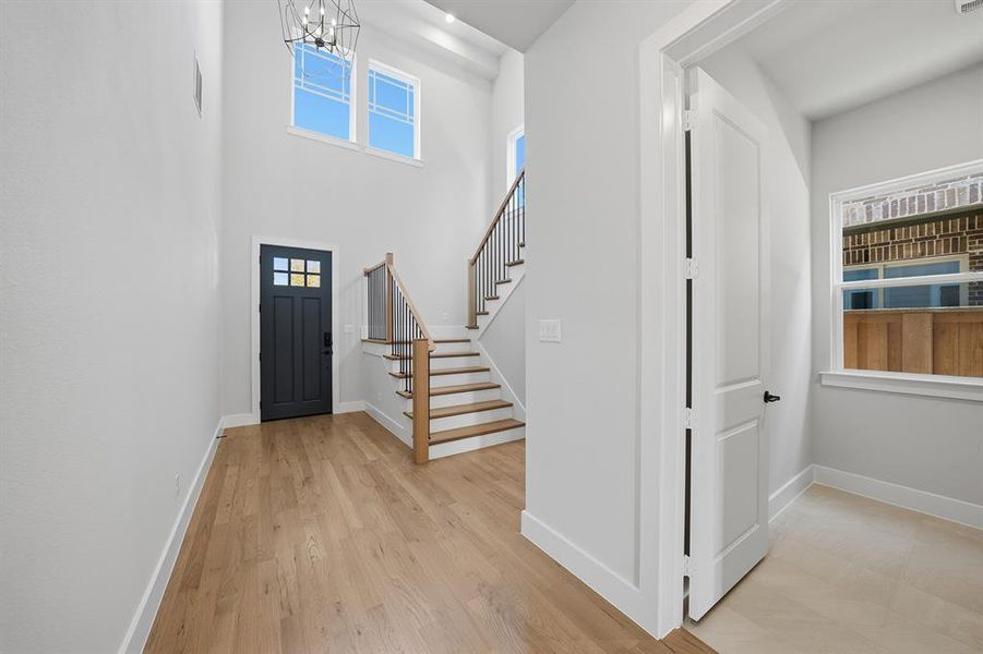 Entrance foyer featuring light wood-style floors, stairs, a high ceiling, and a chandelier