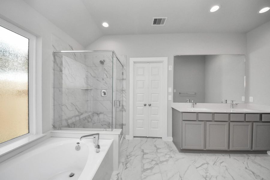 Experience luxury in this spa-like primary bathroom featuring a massive walk-in shower with tile surround. Light colored cabinets with light granite countertops complement the space, alongside a spacious walk-in closet with shelving, high ceilings, custom paint, and sleek, dark modern finishes. An ideal retreat for unwinding after a long day Experience luxury in this spa-like primary bathroom featuring a massive walk-in shower with tile surround. Light colored cabinets with light granite countertops complement the space, alongside a spacious walk-in closet with shelving, high ceilings, custom paint, and sleek, dark modern finishes. An ideal retreat for unwinding after a long day