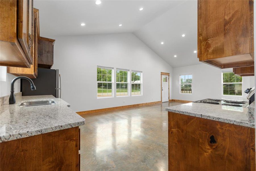 Kitchen featuring a sink, concrete flooring, high vaulted ceiling, baseboards, and recessed lighting Kitchen featuring a sink, concrete flooring, high vaulted ceiling, baseboards, and recessed lighting