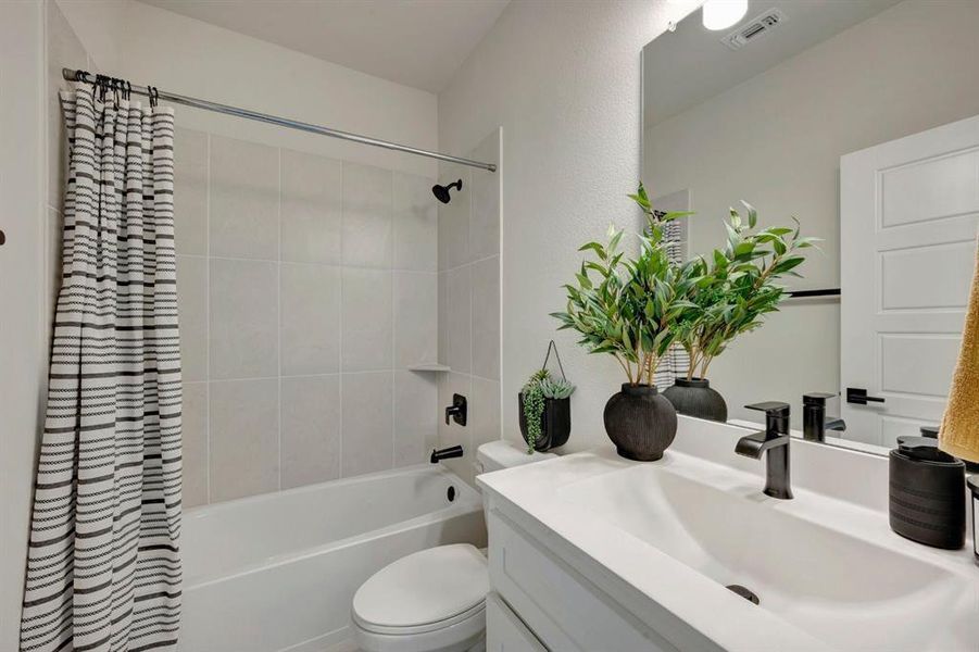 Bathroom featuring a white vanity with an integrated sink, matte black faucet, and a large wall mirror
