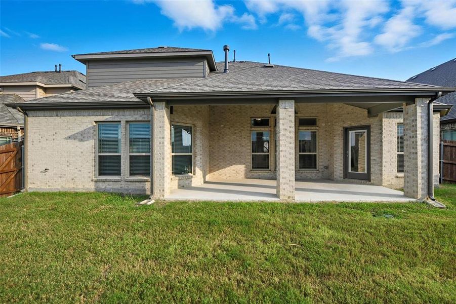 Rear view of house with a patio, a shingled roof, and brick siding Rear view of house with a patio, a shingled roof, and brick siding