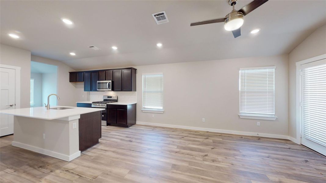 A contemporary open-concept space features a well-appointed kitchen island, sleek appliances, and durable wood flooring. A contemporary open-concept space features a well-appointed kitchen island, sleek appliances, and durable wood flooring.