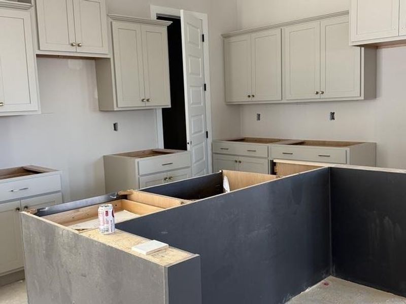 Shaker-style cabinetry, crown molding, and an island with dark-finished base Shaker-style cabinetry, crown molding, and an island with dark-finished base