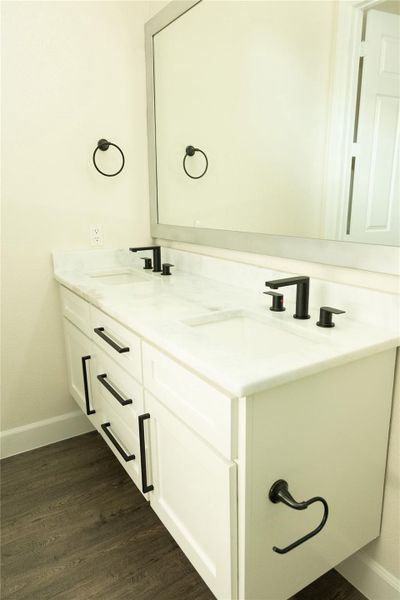 Bathroom with double vanity and dark wood-type flooring