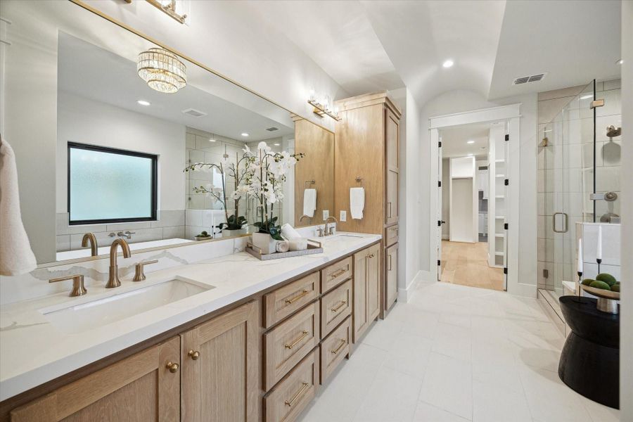 This spacious primary bathroom features a double vanity with elegant oak cabinetry and modern fixtures.